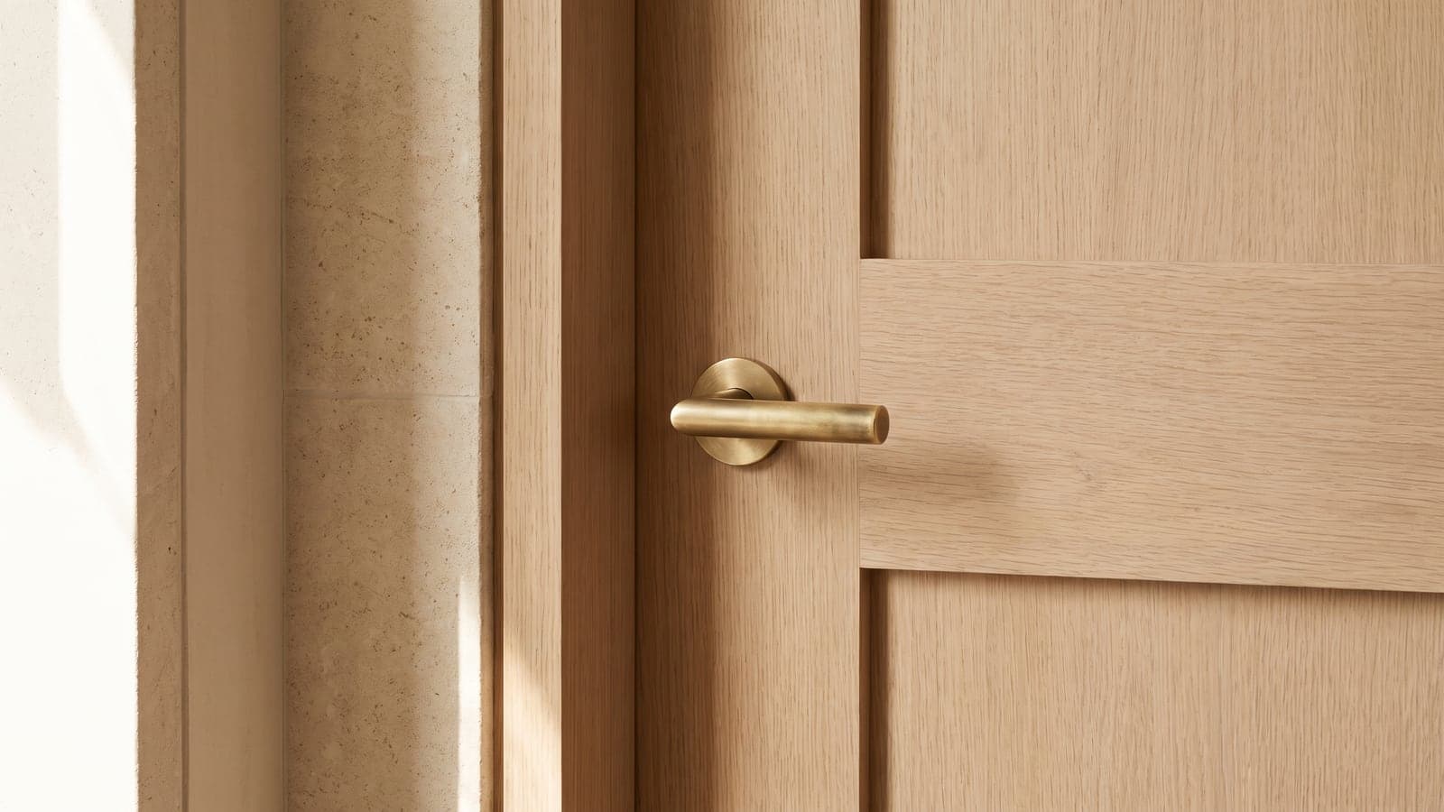 A simple, elegant door handle on a closed pale wood door, quiet architectural light, suggesting privacy and an undisrupted space.