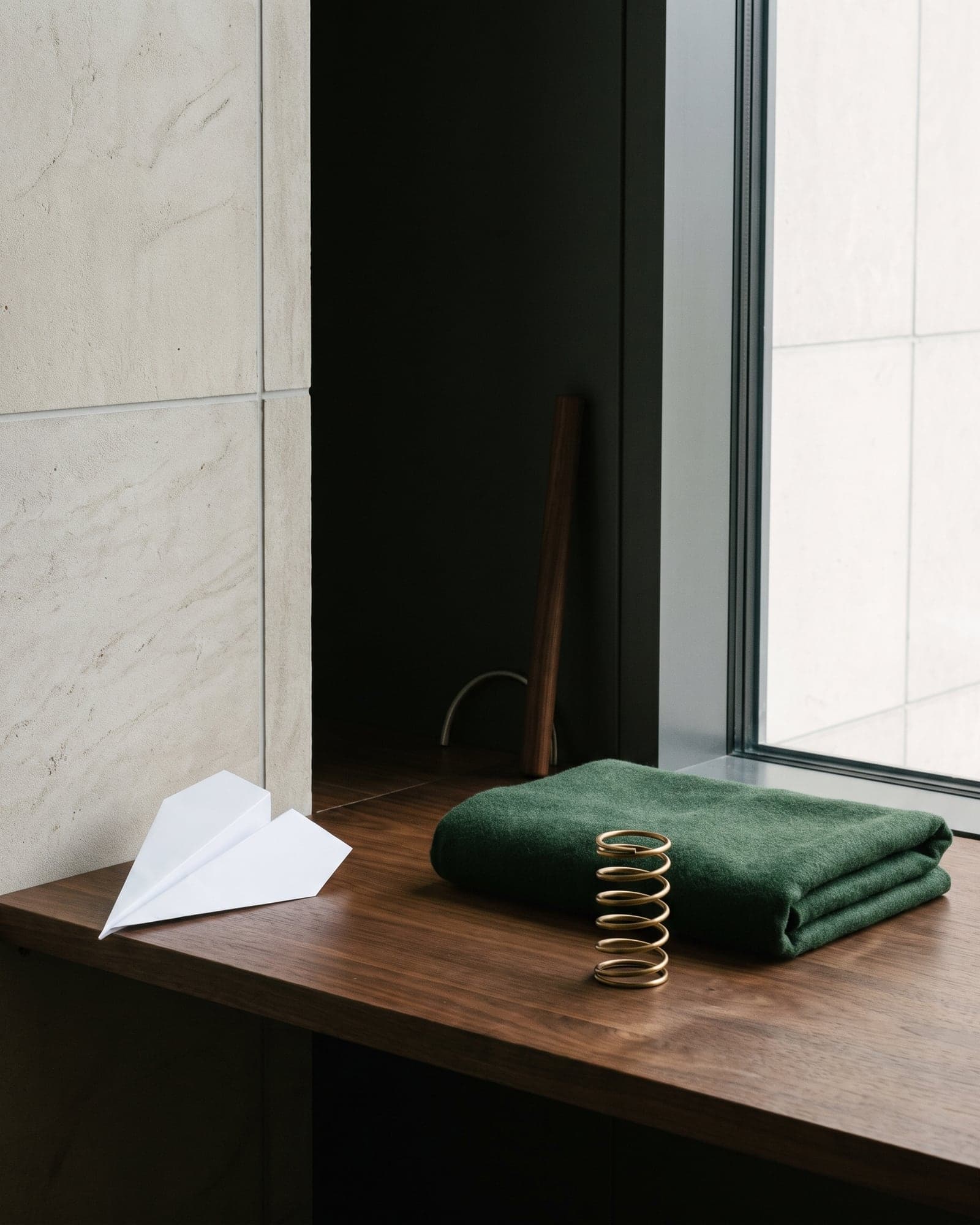 Folded forest textile, brass spring, walnut, and a blank paper plane