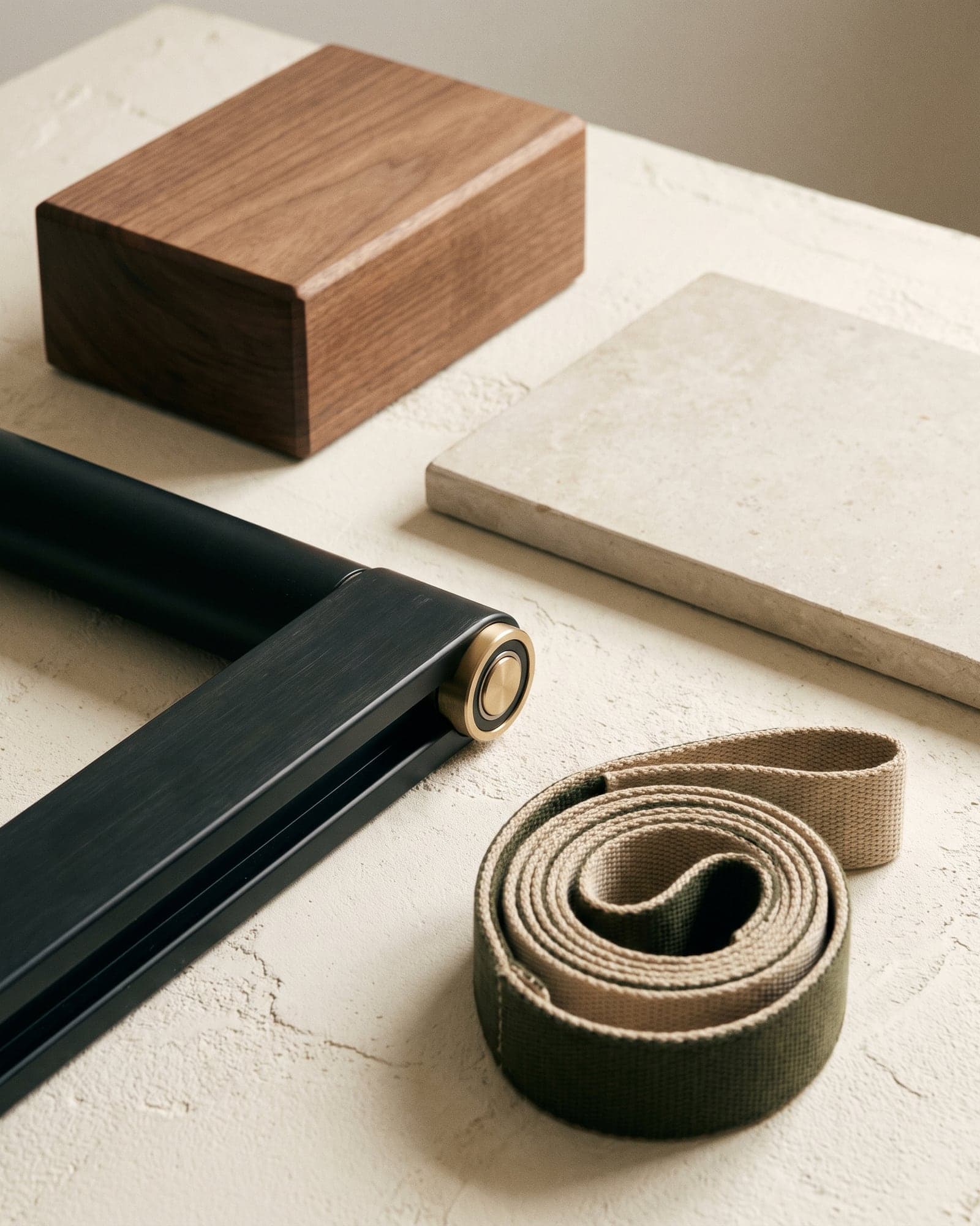 Unbranded reformer rail, woven strap, and walnut block against limestone